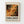 May include: Framed abstract art poster mounted on white wall. Wooden frame contains cream matted print featuring chaotic paint splatters and drips in orange, black, cream, and red tones reminiscent of Jackson Pollock's drip painting style. Bold black text reads "POLLOCK" with subtitle "EMBRACE THE CHAOTIC REALM OF CREATIVITY" and exhibition dates. Dynamic splattered paint creates energetic movement across the composition with dots and flowing lines.
