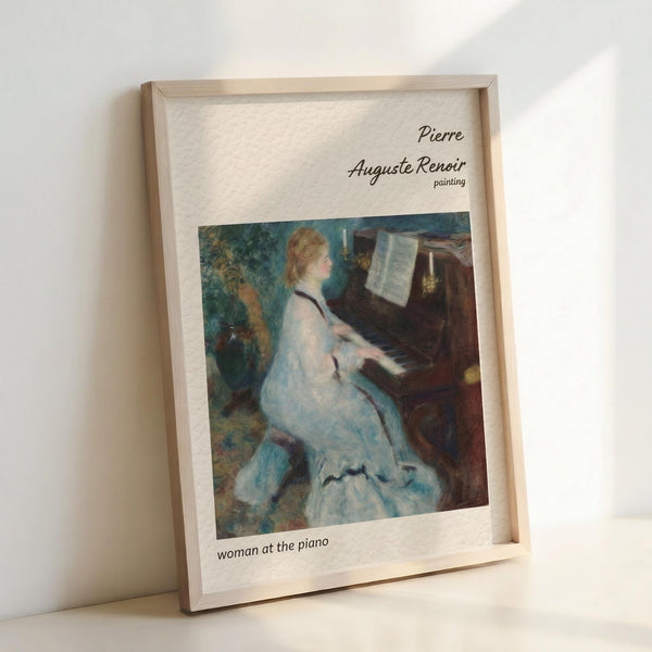 May include: Framed art print showing Renoir's impressionist painting of a blonde woman in a flowing white dress seated at a dark wooden piano, reading sheet music. The artwork features soft brushstrokes in blues, whites, and earth tones with foliage visible in the background. Light wooden frame sits propped against white wall, casting gentle shadows on neutral surface below.