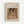 Framed vintage-style art print featuring Pierre Auguste Renoir's painting of a woman with dark hair wearing an orange headband and pearl necklace. The artwork shows soft, impressionistic brushstrokes in warm tones of peach, orange, and cream. Text above reads "Pierre Auguste Renoir painting" and below reads "woman with black hair." Natural wood frame with cream matting, displayed against a light background.