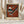 May include: Framed museum poster print of Wassily Kandinsky's abstract artwork featuring geometric shapes in rust orange, black, white, and teal colors. The vintage-style print shows triangular and linear forms with small circles against a weathered background. Displayed on white surface with dried pampas grass stems on both sides and soft beige curtains behind.