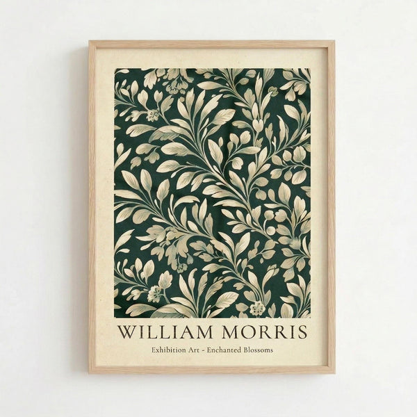 May include: Framed botanical art print in light wood frame hanging on white wall. Features dark green background with cream-colored flowing leaves, branches and small flowers in decorative Arts and Crafts style pattern. Text below reads "William Morris Exhibition Art - Enchanted Blossoms" in serif font on cream matting.