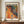 May include: Framed art print with colorful abstract polka dot pattern in orange, yellow, and multicolored circles against black background, displayed on wooden console table next to white ceramic vase and stacked books in elegant room with white walls and molding.