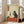 May include: Framed artwork displayed in bright living room next to beige sofa and windows. The print shows a black cat in traditional Japanese ukiyo-e style sitting at red table, holding wine glass, with wine bottle, grapes, and cheese nearby. Features aged parchment background with orange Japanese text banner in upper left corner.