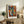 May include: Framed abstract cubist-style artwork featuring colorful geometric faces in blues, oranges, and yellows displayed on rustic wooden sideboard alongside fern plant, ceramic vases, and books in modern living room with beige armchair and neutral walls
