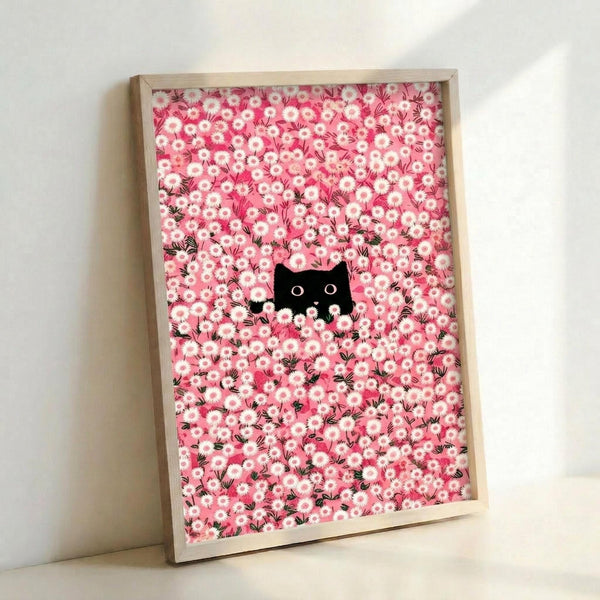 May include: Framed artwork leaning against white wall showing pink and white daisy floral pattern with small black cat silhouette peeking through flowers. Natural wood frame, approximately 12x16 inches, displayed in bright indoor setting with soft lighting and shadows.