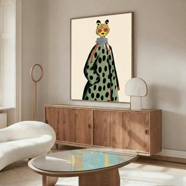 May include: Contemporary living room with wooden sideboard displaying framed artwork of stylized leopard figure wearing green polka dot dress with blue collar. White upholstered chair, brass floor lamp, clear table lamp, and oval glass coffee table with colorful abstract art visible underneath complete the mid-century modern interior scene.
