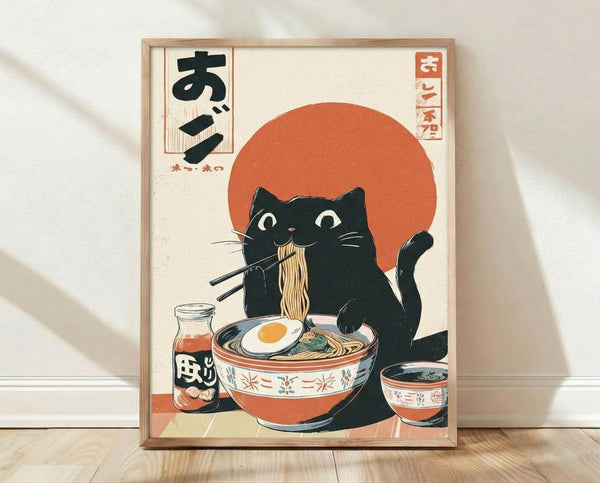 Framed poster featuring a black cat with white eyes eating ramen noodles with chopsticks, set against a large orange sun. The cat sits beside a decorative bowl filled with noodles, egg, and garnishes, with additional small bowls and a bottle nearby. Japanese text appears in the corners. The artwork uses a vintage Japanese woodblock print style with muted colors on cream background. The wooden frame leans against a white wall on light wood flooring.