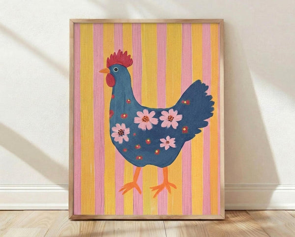 May include: Framed poster print featuring a stylized blue hen with red comb and wattles, decorated with pink flowers across its body, standing on orange feet against vertical yellow and pink striped background, displayed in light wood frame leaning against white wall on wooden floor.