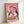 May include: Framed poster print leaning against white wall showing two white geese wearing sunglasses and scarves sharing pizza and red wine on pink and purple background. Light wood frame, painterly illustration style with visible brushstrokes, whimsical romantic dinner scene.