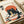 A vintage-style Japanese ukiyo-e print featuring a black cat with white chest markings eating ramen noodles from a decorative bowl with chopsticks. The cat sits against a large orange sun backdrop with Japanese text characters visible in the corners. The artwork uses a cream background with orange, black, and muted color palette in traditional woodblock print style. The print is displayed on white paper alongside rolled paper tubes on a light wooden surface.