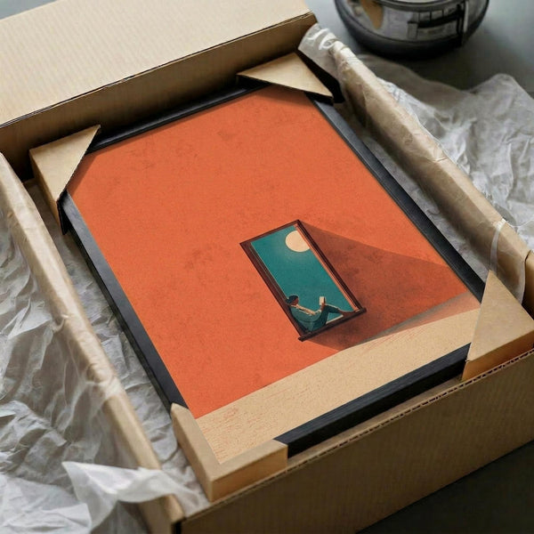May include: Framed art print being carefully unpacked from cardboard shipping box with protective tissue paper. The contemporary artwork features a minimalist orange background with a geometric doorway or window opening revealing a teal interior scene with a figure reading beneath a crescent moon. The piece has clean lines and modern color blocking in warm coral and cool turquoise tones, shown in a simple black frame.