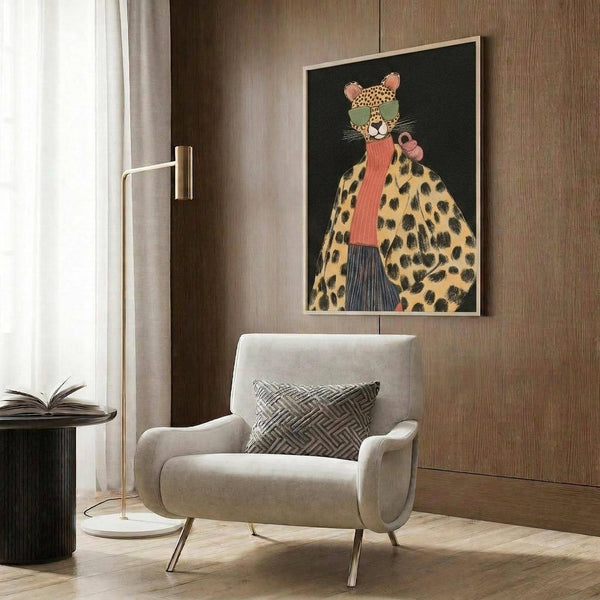 May include: Stylized cheetah wearing green sunglasses, coral scarf, and leopard print coat displayed in framed artwork on wood-paneled wall above beige upholstered chair with geometric pillow, gold floor lamp, and dark round side table with open book in modern living room setting