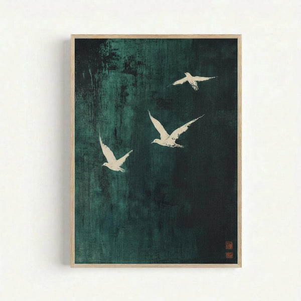 Framed artwork featuring three white birds in flight against a dark teal and black textured background. The birds appear to be cranes or herons rendered in minimalist Japanese ink painting style. The piece has a weathered, vintage appearance with visible brush strokes and texture throughout the background. Two small red seal stamps appear in the bottom right corner. The artwork is displayed in a light wood frame against a white wall.