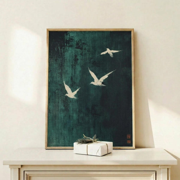 May include: A framed artwork featuring white birds in flight against a dark teal and black textured background, displayed on a light wood console table alongside a small wrapped gift with twine. The piece has an Asian-inspired ink painting style with a weathered, vintage appearance and appears to include a small red seal mark in the corner.