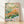 Impressionist framed art print of a songbird perched among wildflowers in soft pinks, oranges, and sage greens, evoking a serene pastoral garden.