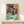 Framed poster of a girl engrossed in a book within a warmly-colored interior space, using rich jewel tones and decorative elements to convey peaceful contemplation.