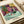 Art print framed on wall depicting a girl lost in a book within a luminous, contemplative interior rendered in vivid yellows, blues, reds, and greens.