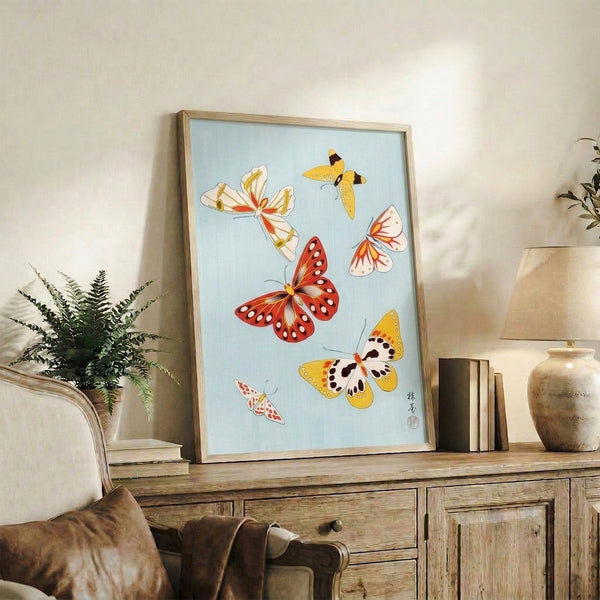 Framed wall art depicting gracefully rendered butterflies in warm and cool tones—red, gold, black lines, and cream-blue ground—in the style of classical Japanese woodblock art.