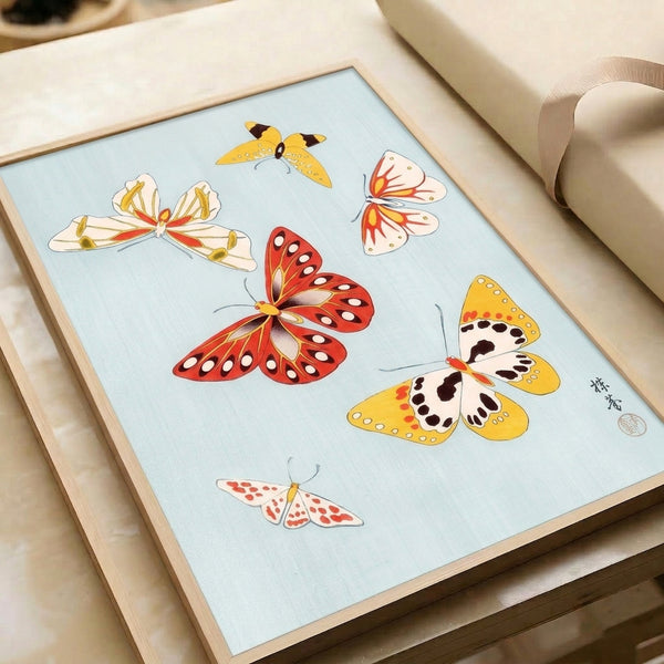Refined butterfly composition featuring delicate wings rendered in red, gold, and black on a soft blue background, displayed as a framed poster with serene, meditative character.