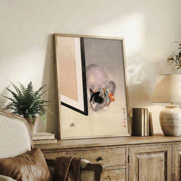Whimsical framed artwork of a cat adorned with ribbon in traditional Japanese woodblock aesthetic, combining grey and cream tones with red-orange and turquoise details for a contemplative mood.