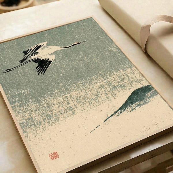 Red-crowned crane in mid-flight above forested peaks, rendered as a zen-inspired woodblock print in soft sage green, cream, and black on a framed wall poster.