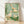Serene Japanese woodblock-style poster depicting ducks nestled among reeds in a peaceful pond, rendered in soft sage green, cream, and pale yellow tones with dark green accents, framed on a wall.