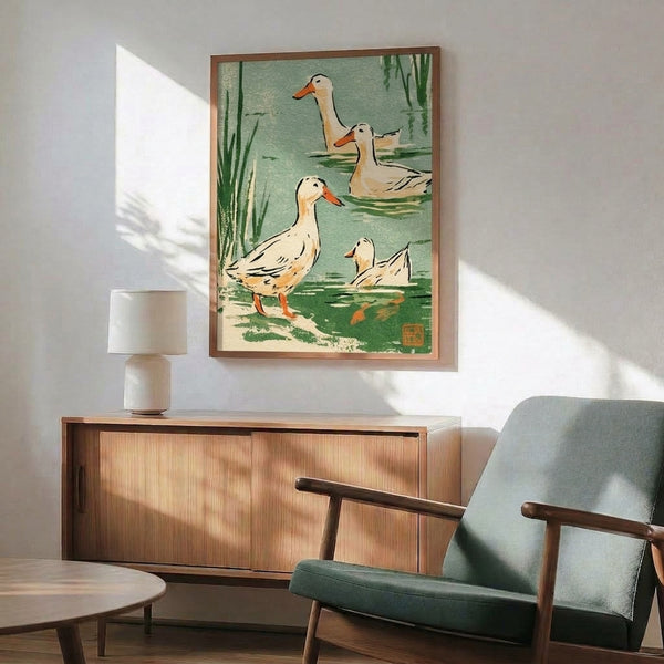 Framed poster art showing a tranquil pond scene with ducks and reeds in muted earth tones including sage green, cream, and pale yellow, executed in a classic Japanese woodblock aesthetic.