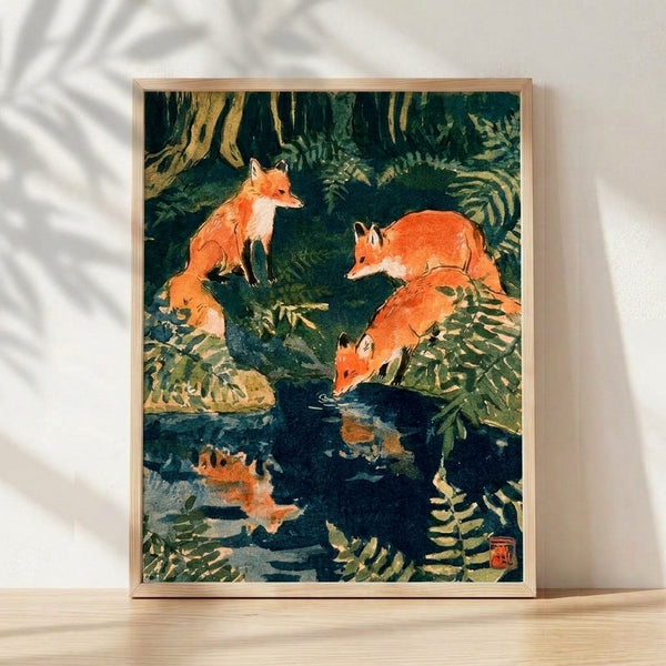 Framed Japanese-inspired ink wash poster depicting two rust-colored foxes beside a forest stream surrounded by ferns and trees in forest green and deep teal tones, creating a serene and contemplative mood.