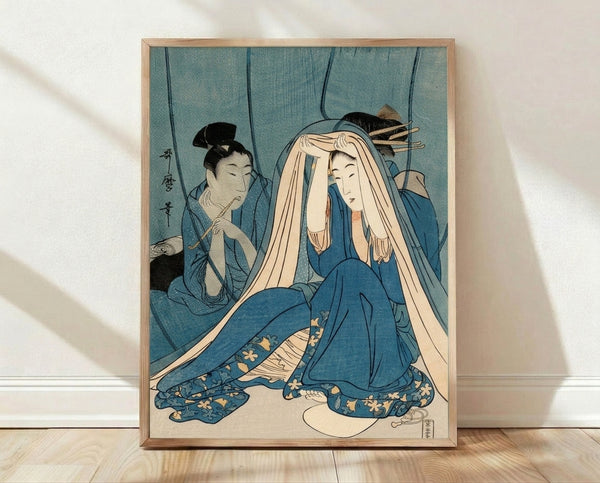 Japanese woodblock print depicting a serene geisha gazing into a mirror, rendered in soft teal blue, cream, and black with gold ochre accents, framed and hung on a wall.
