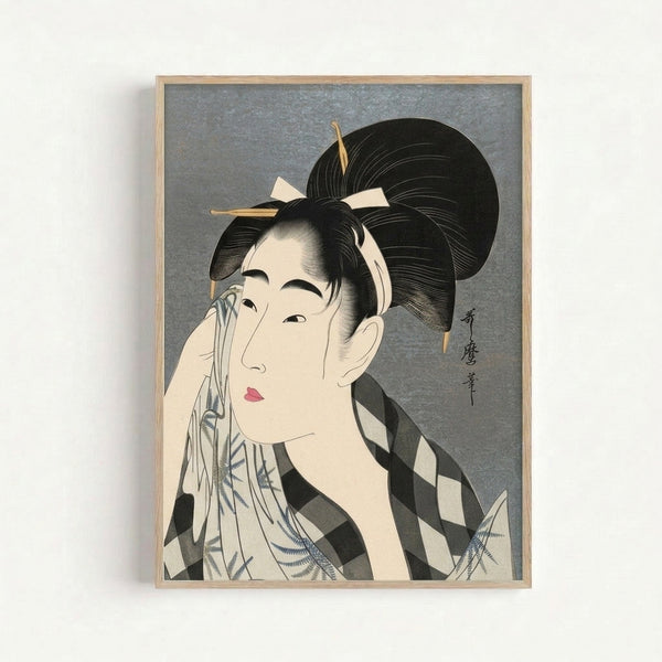 Framed ukiyo-e style artwork depicting a geisha with elaborate hair and makeup adjusting her face, displaying refined brushwork in muted cream and blue palette.