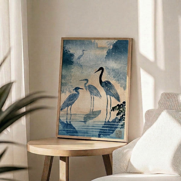 Traditional Japanese bird painting of herons in a mist-shrouded wetland with bamboo forest, rendered in slate blue and cream palette, framed as wall art.