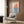 Framed minimalist poster of a Japanese junk with billowing sails, rendered in nostalgic burnt orange, deep blue, and cream palette on gallery wall.