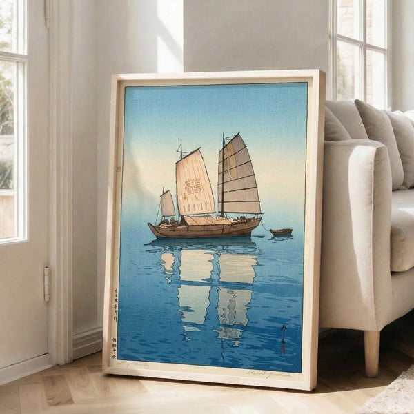 Serene Japanese coastal print showing a sailboat with full sails and mirror reflection below, executed in soft cream, blue, and grey tones in classic woodblock style.