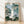 Serene waterfall cascading down a misty mountain cliff surrounded by forest trees, rendered in soft watercolor tones of sage green, pale blue, and cream in a vintage Japanese woodblock style.