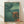 Framed Japanese woodblock art print featuring two ornate samurai helmets in profile facing each other, rendered in deep teal, forest green, and copper gold tones with a dignified, martial aesthetic.