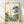 Serene Japanese woodblock-style landscape poster featuring a teapot pouring a flowing stream through bamboo and flowering plants, rendered in cream, navy blue, sage green, and coral tones with gold accents.