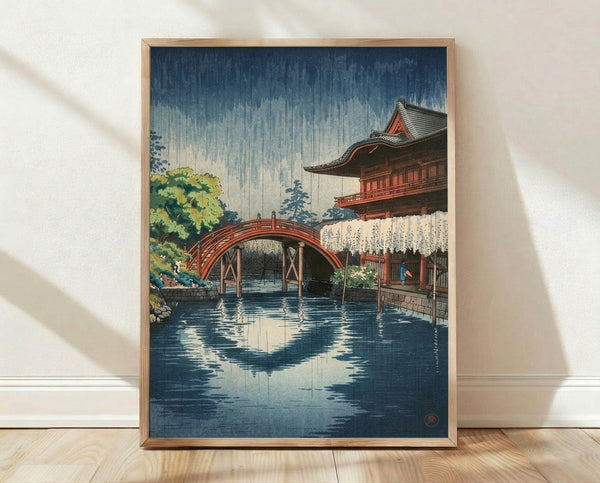 Serene Japanese woodblock print depicting a rain-soaked temple bridge with traditional architecture, rendered in deep blue, cream, and muted earth tones.