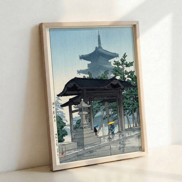 Framed art print featuring a tranquil Japanese temple gate during rainfall, rendered in delicate woodblock style with forest green and light blue hues.