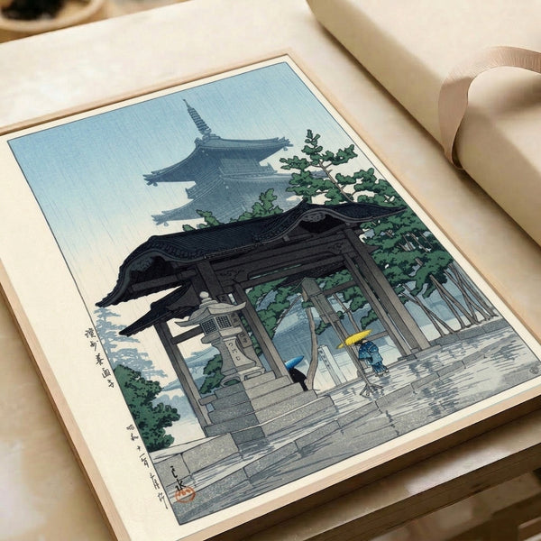 Vintage framed print depicting serene figures with umbrellas at a rain-dampened temple entrance and pagoda, rendered in tranquil blue-green and cream palette.