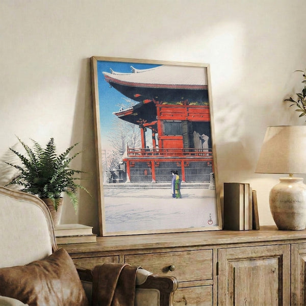 Contemplative Japanese woodblock art depicting a kimono figure at a snow-blanketed temple, cool cerulean and cream palette creating quiet, meditative atmosphere on framed poster.