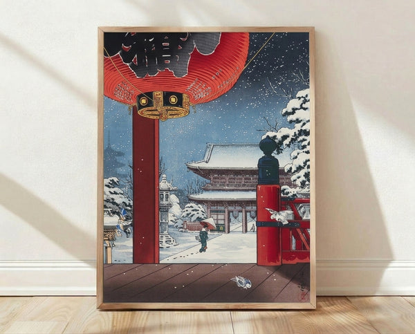 Serene Japanese woodblock-style winter scene depicting a snow-covered temple with red lantern, traditional gate, and solitary figure among trees in shades of blue, white, and gold.