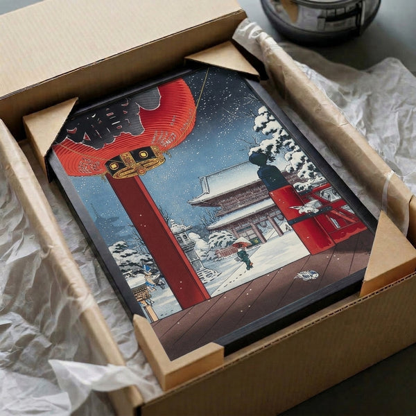 Wall art print capturing the quiet mood of a snow-laden Japanese temple grounds with glowing red lantern, traditional architecture, and single figure standing beneath wintry branches in blues and golds.