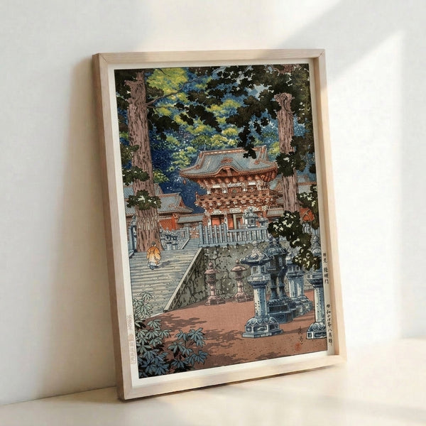 Framed Japanese temple woodblock print depicting the atmospheric entrance to Nikko Toshogu shrine with forest greens, sky blue sky, and a solitary monk among ceremonial elements.