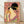 Framed Japanese woodblock print of an elegant geisha in a coral pink and gold kimono, holding a decorative fan with contemplative expression amid soft florals and mauve tones.