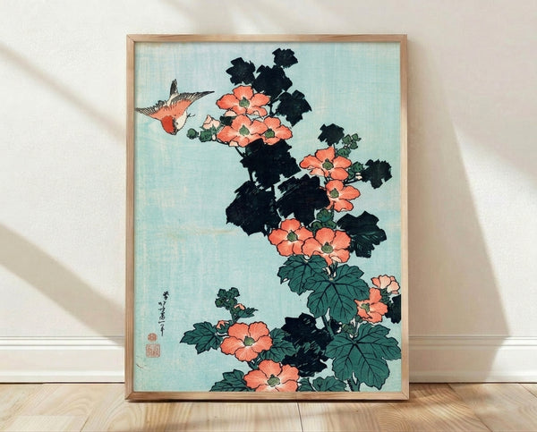 Framed Japanese woodblock print of a serene bird perched among coral-red hibiscus flowers and sage green leaves, rendered in soft pale blue-green and cream tones with deep black ink lines.