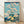 Serene Japanese woodblock landscape poster featuring Mount Fuji framed by cherry blossoms in soft cream and pale yellow, with prussian blue water and teal accents.