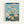 Contemplative Japandi art print depicting a peaceful mountain scene with blooming cherry trees, traditional architecture, and figures in harmonious cream, blue, and black tones.