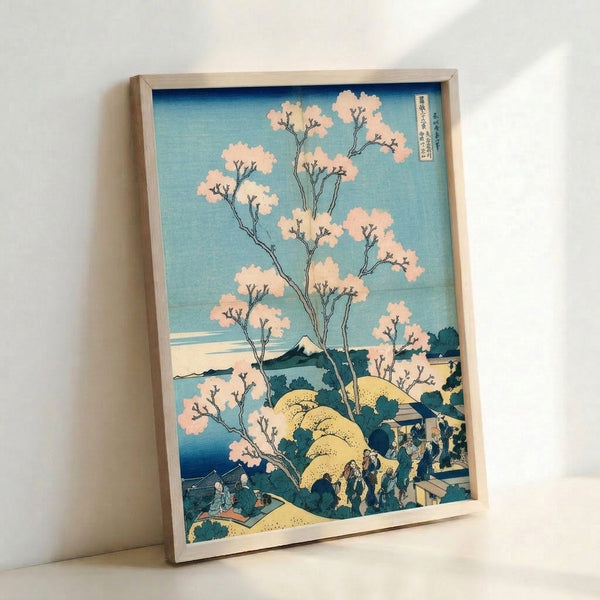 Framed vintage-style woodblock poster of Mount Fuji surrounded by cherry blossoms, rendered in muted prussian blue, pale yellow, and cream with a meditative atmosphere.