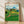Serene Japanese woodblock landscape print depicting emerald tea fields rolling toward distant mountains, with a sailboat on deep blue water and cream sky with soft clouds, evoking nostalgic pastoral charm.