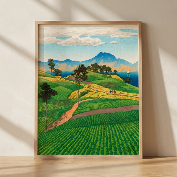 Serene Japanese woodblock landscape print depicting emerald tea fields rolling toward distant mountains, with a sailboat on deep blue water and cream sky with soft clouds, evoking nostalgic pastoral charm.